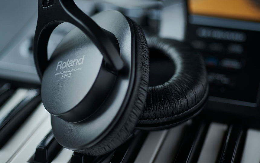 Black Roland RH-5 headphones, close-up of earcups and cushions on piano keys