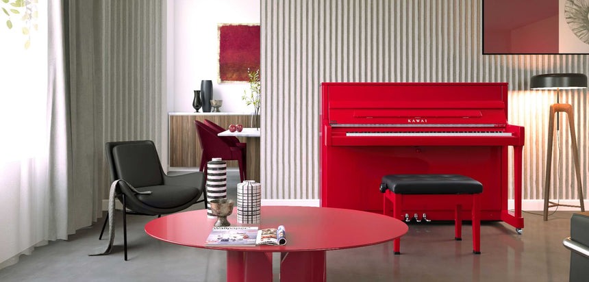 Piano droit Kawai K-200 rouge brillant – vue de face dans un salon avec banquette noire.